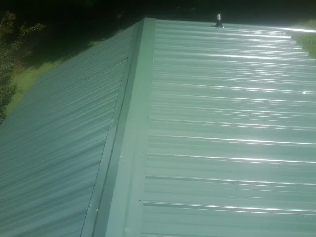 New green metal panels meeting at the ridge of a roof — Flat Roof Repair work by our crew in Boyd
