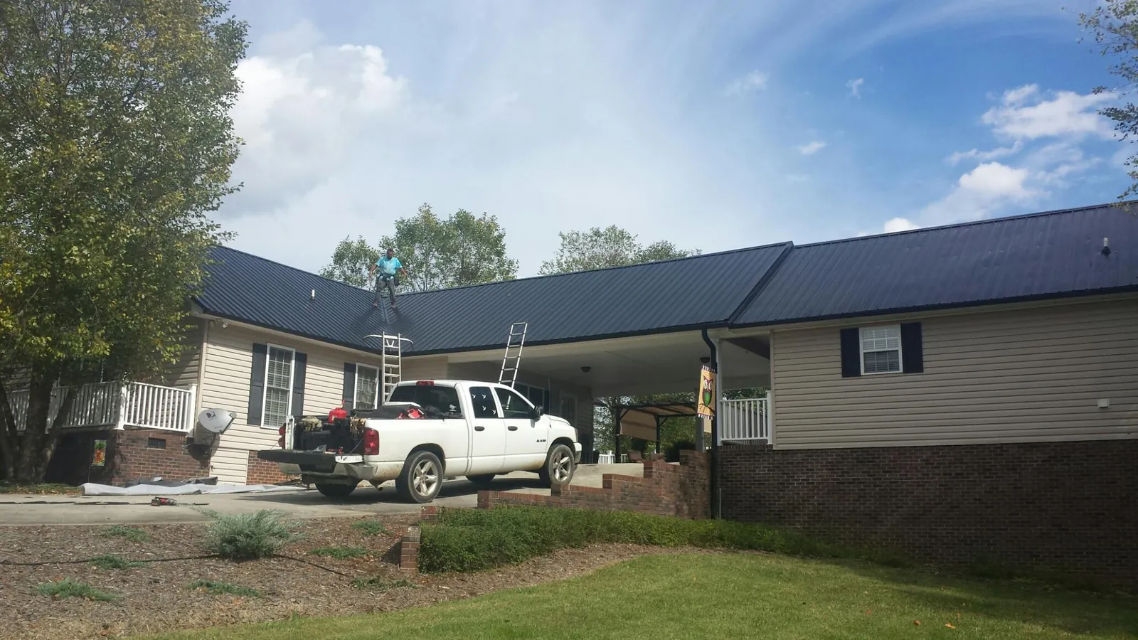 Black metal roof over a home and attached breezeway with ladders set in Boyd